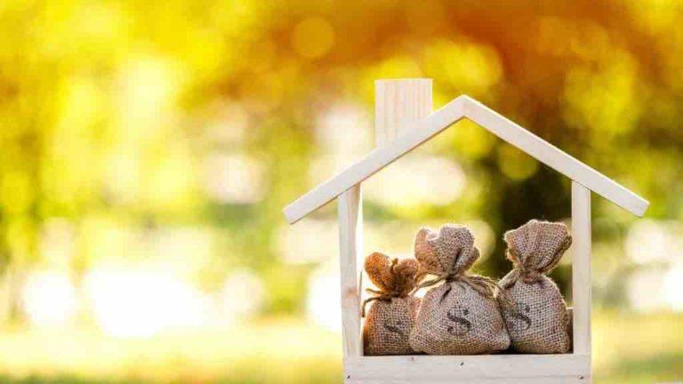Gebasteltes Holzhaus mit kleinen Geldsäckchen